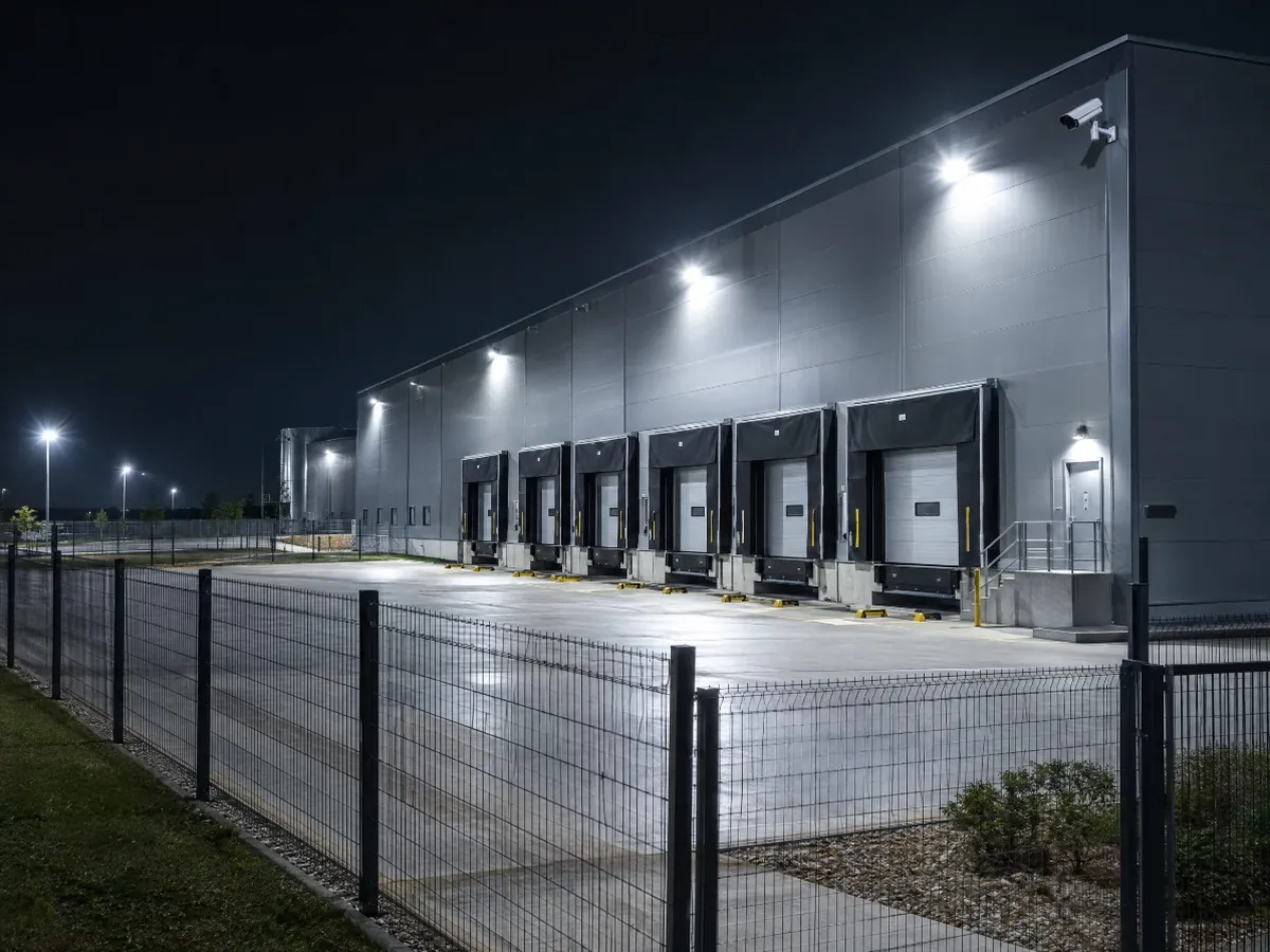 Logistikhalle mit Laderampe, Flutlicht und Außenkamera bei Nacht